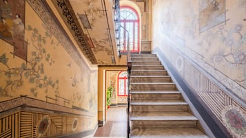 Una imponente escalera adornada con decoraciones en las paredes y una puerta roja en la parte superior.