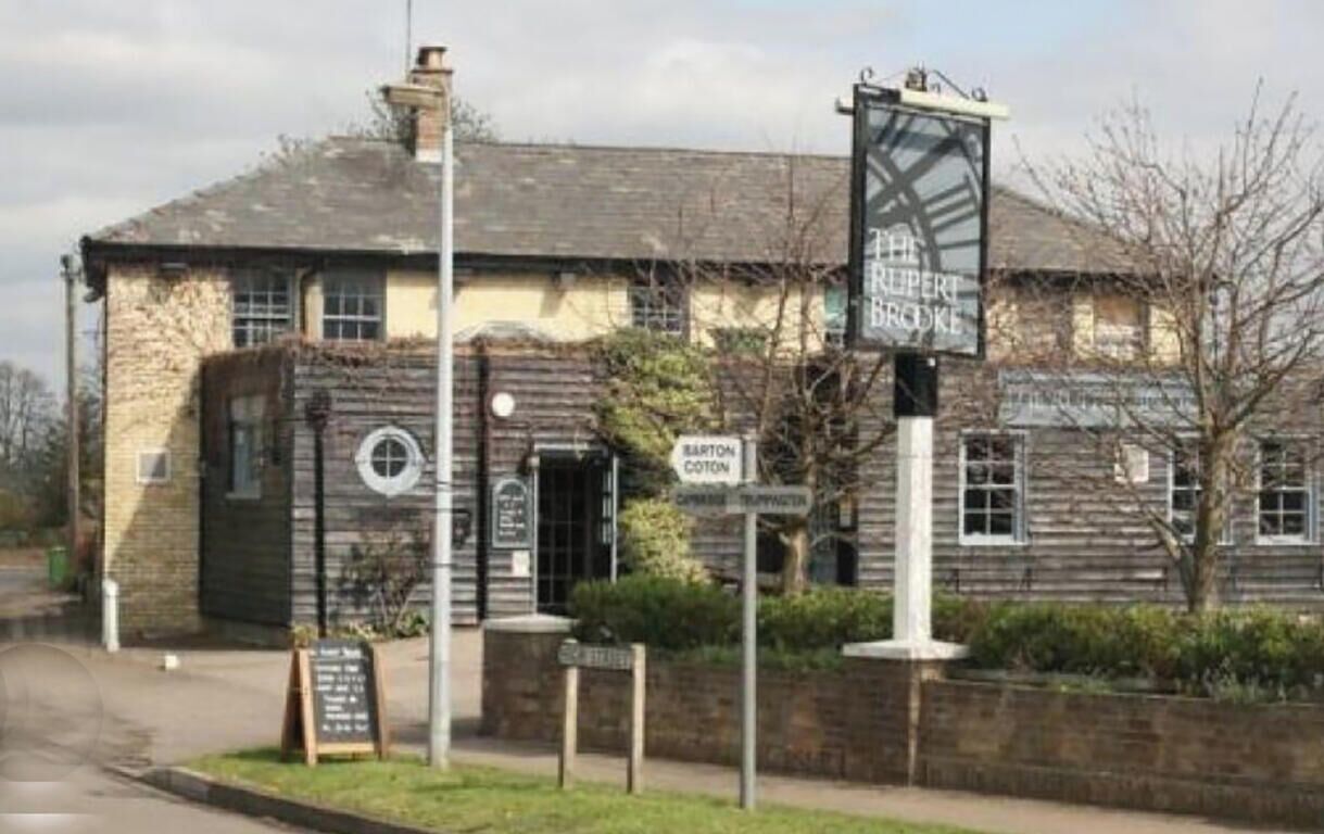 A traditional building with a signboard indicating 'The Rupert Brooke' and 'Baron Cotton'.