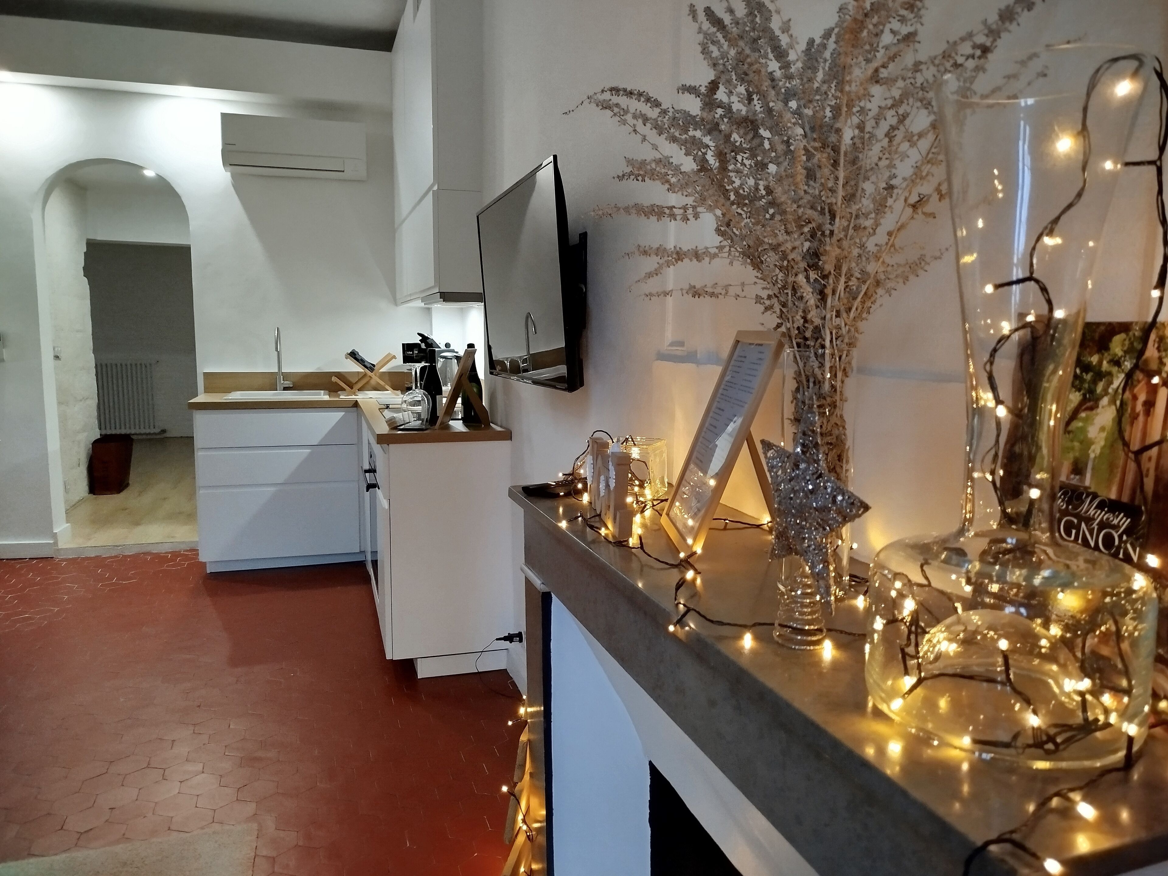 A modern kitchen with white cabinets, a built-in oven, and a flat-screen TV mounted on the wall.