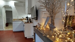 Une cuisine moderne avec des armoires blanches, un four encastré et un téléviseur à écran plat fixé au mur.