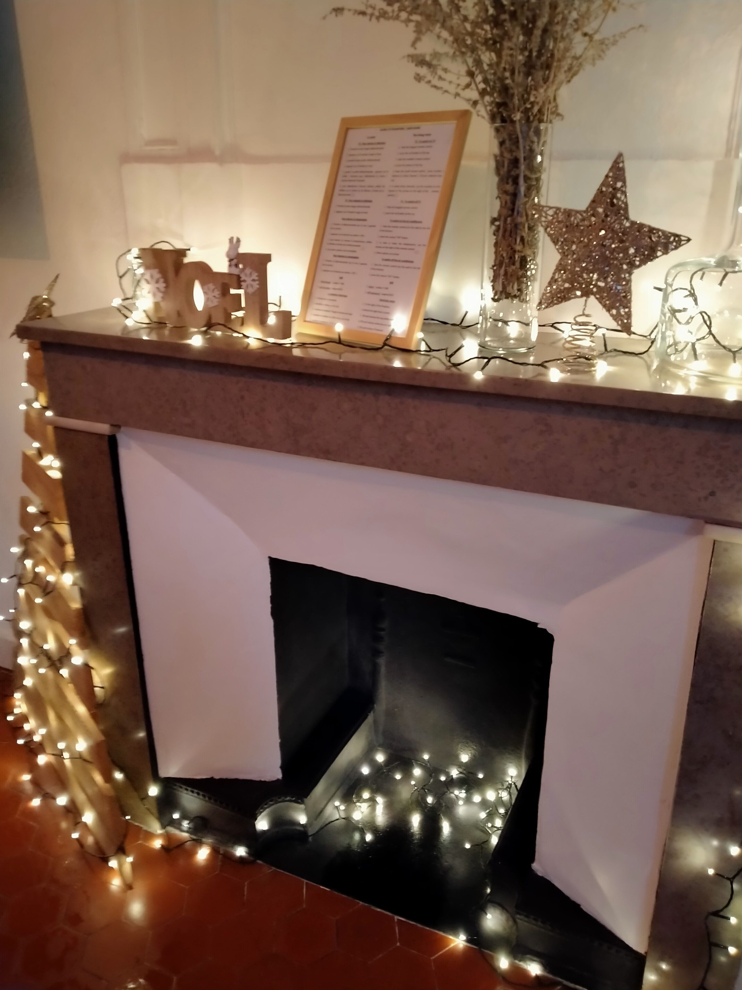 A fireplace with a menu board, decorative lights, and a star ornament.