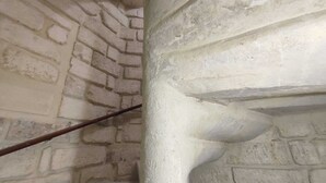 Un escalier avec un mur de briques d’un côté et un pilier blanc de l’autre.
