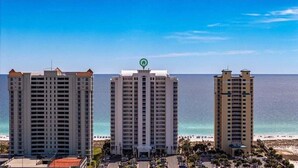 Drei hohe Hotels mit Balkonen mit Blick auf einen Strand und den Ozean.