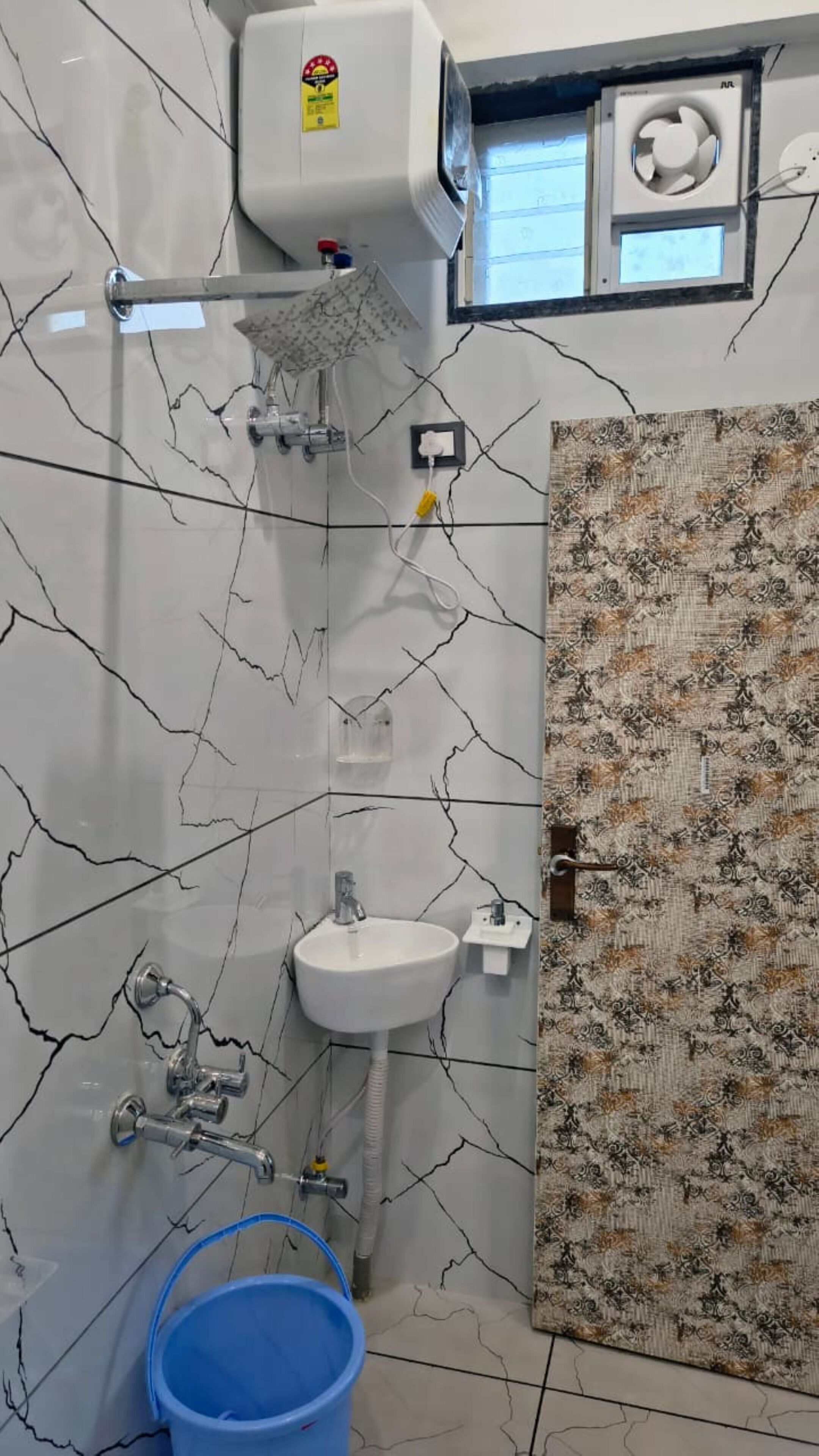 A bathroom with a white sink, a shower, and a blue bucket.