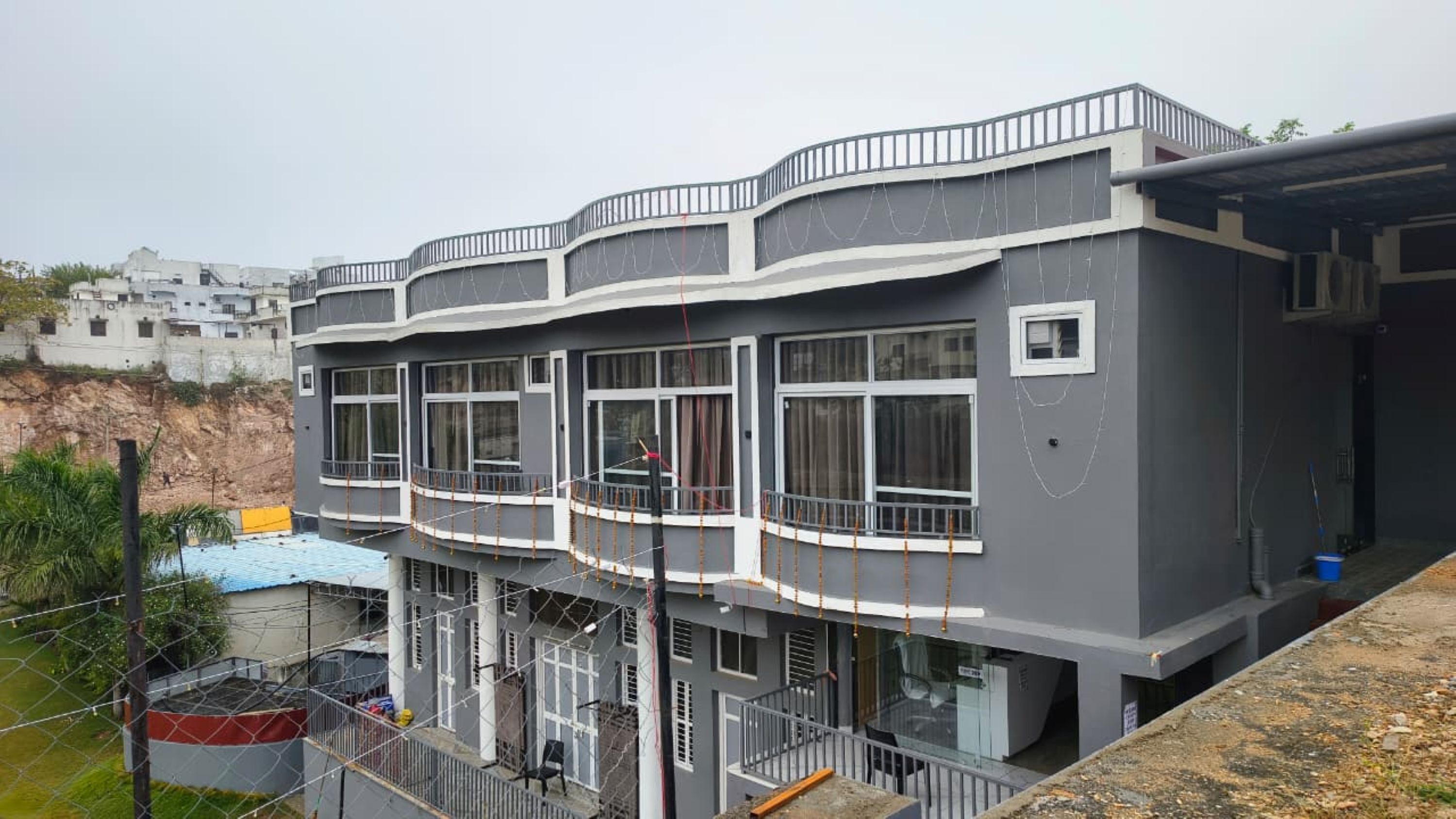 A multi-story residential building with balconies, large windows, and a grey facade.
