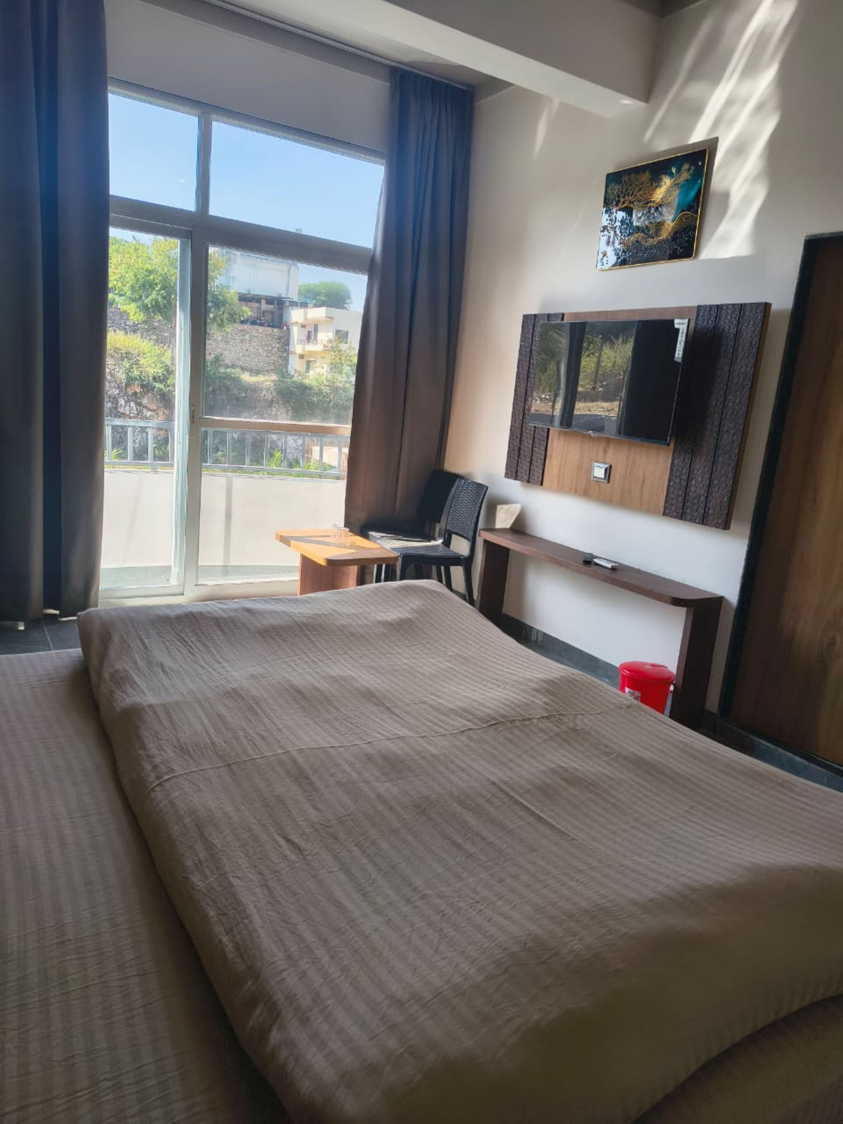 Une chambre d’hôtel avec un grand lit, un bureau, une chaise et un téléviseur fixé au mur.