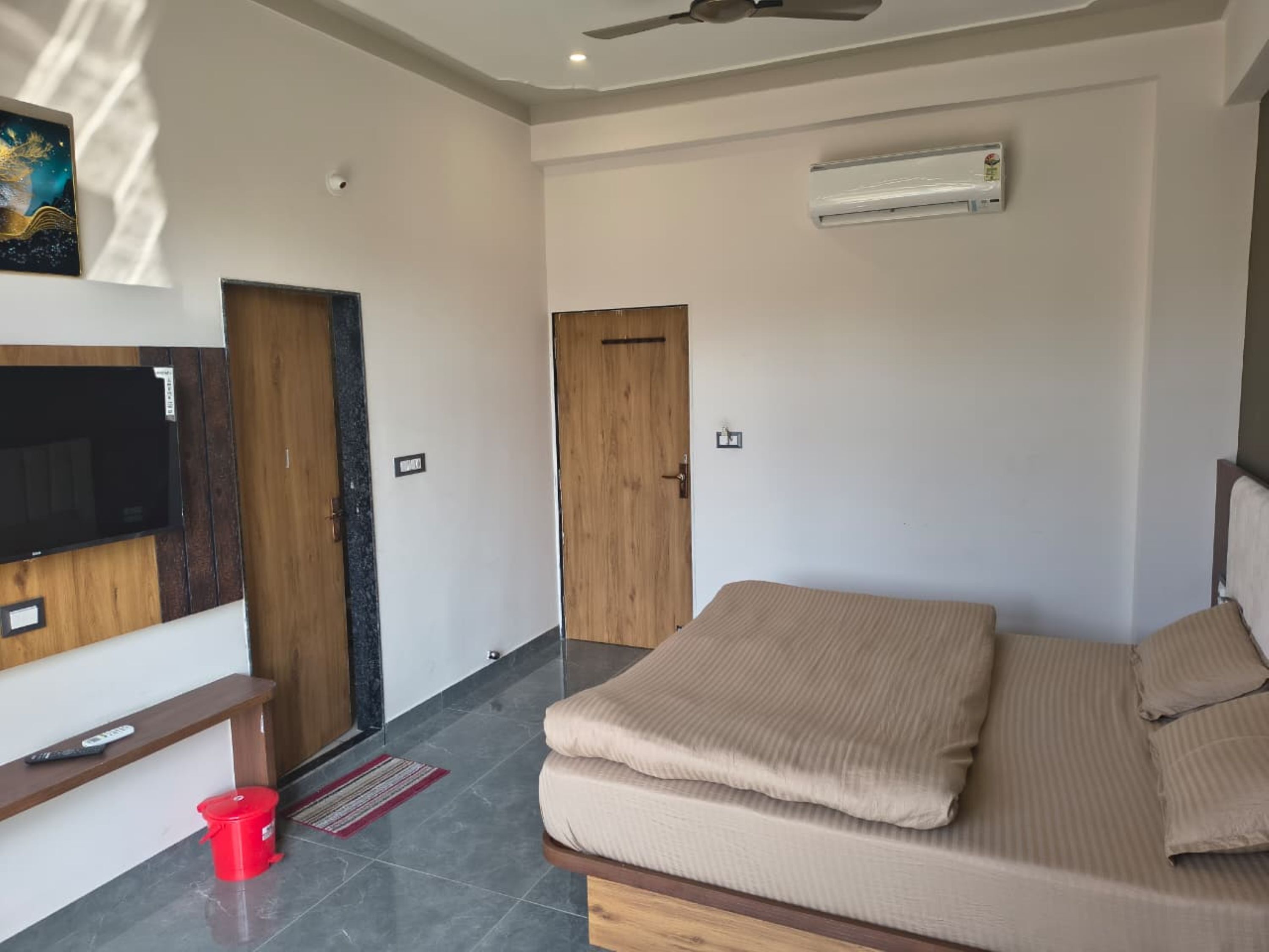 Een slaapkamer met een bed, televisie, plafondventilator en een airconditioning.