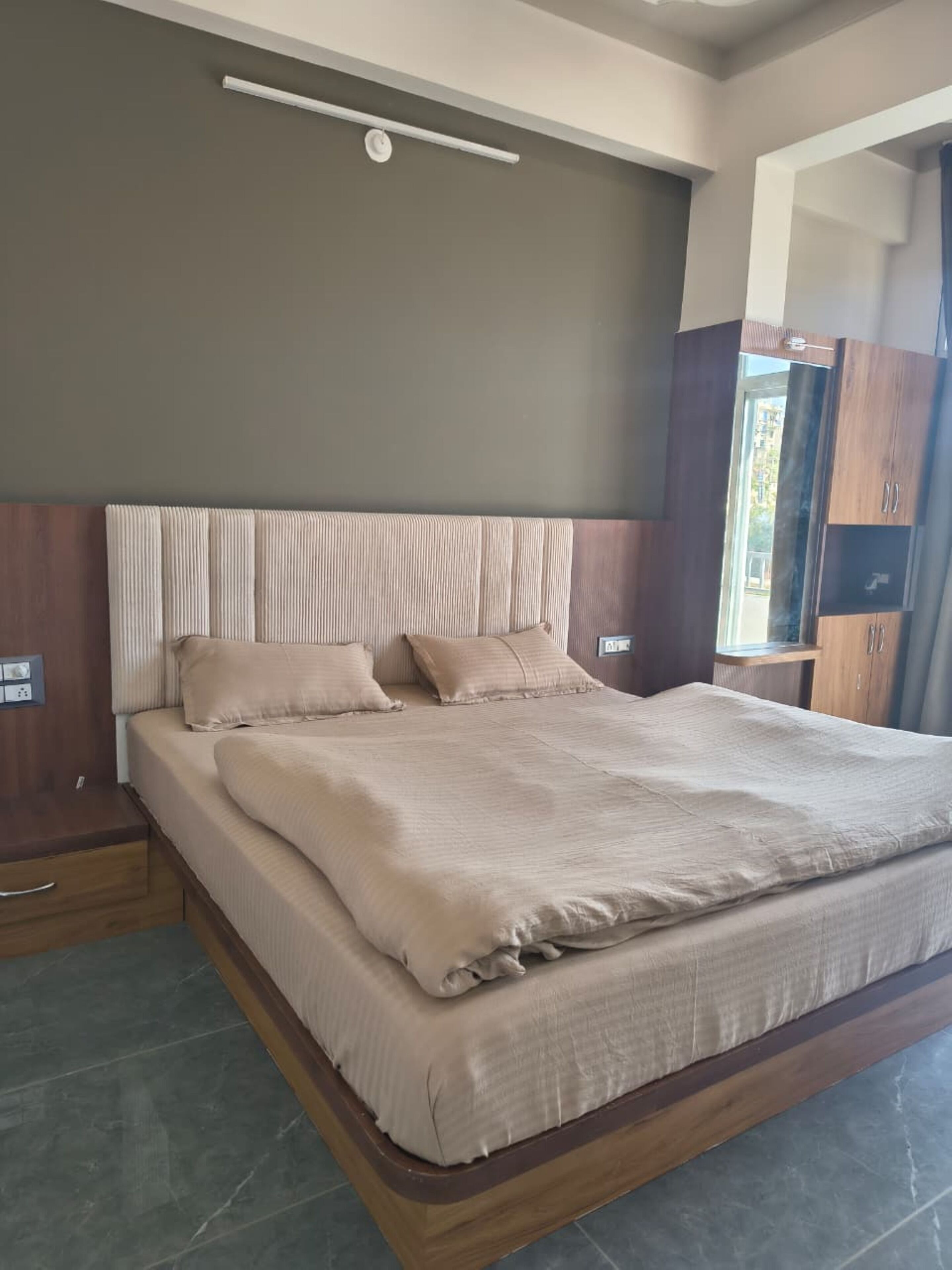 A modern bedroom with a large bed, wooden headboard, and built-in wardrobe.