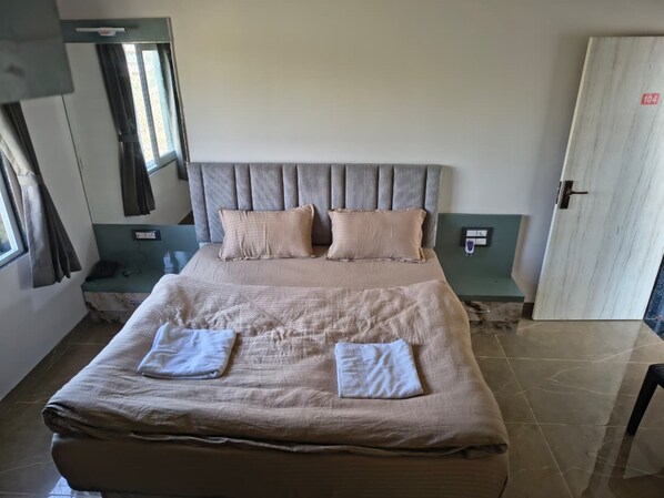 A neatly made bed with two pillows and two folded towels. - Shree Vallabh Resort (Nathdwara)