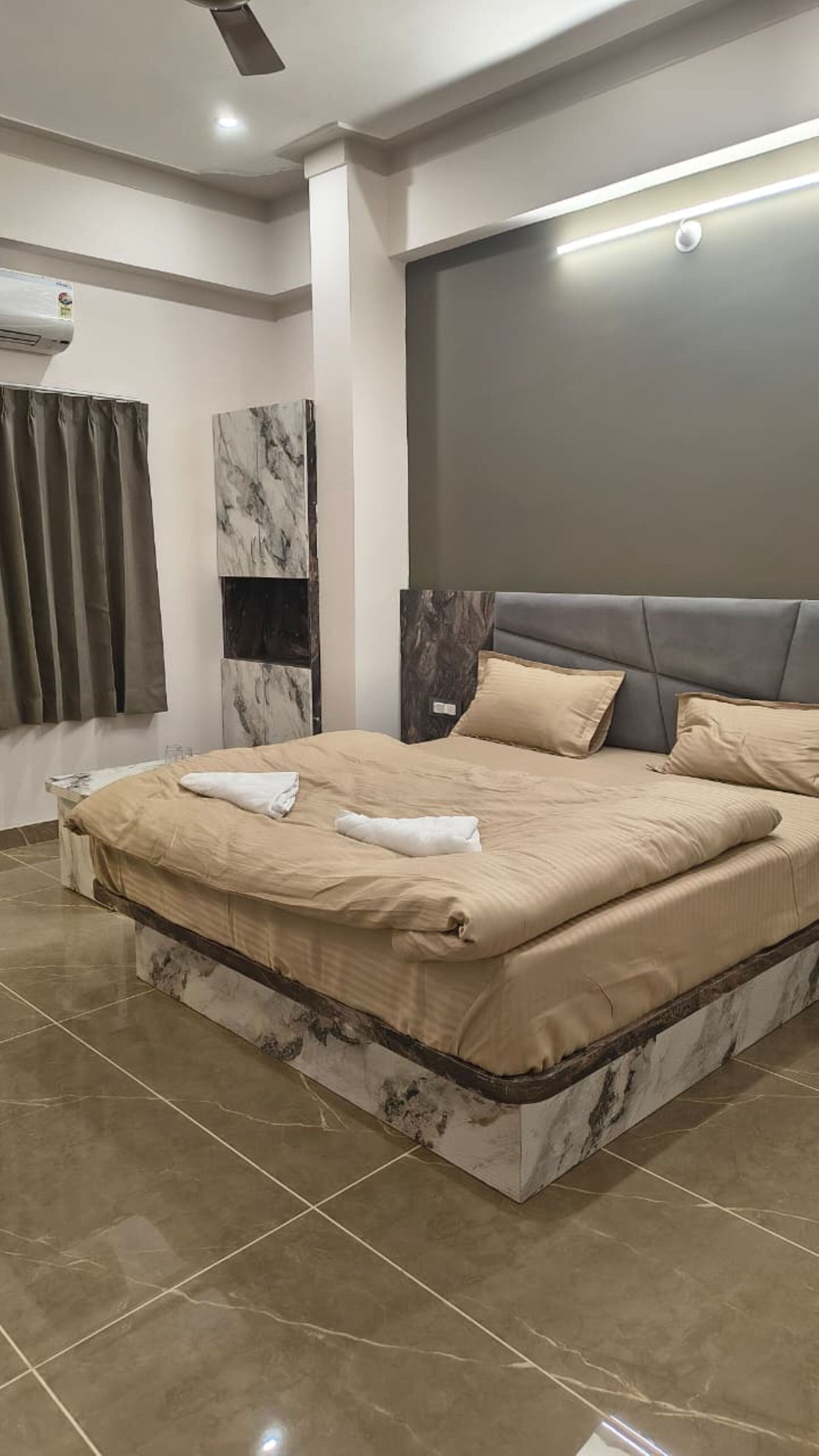 A modern bedroom with a large bed, marble headboard, and a wall-mounted TV.