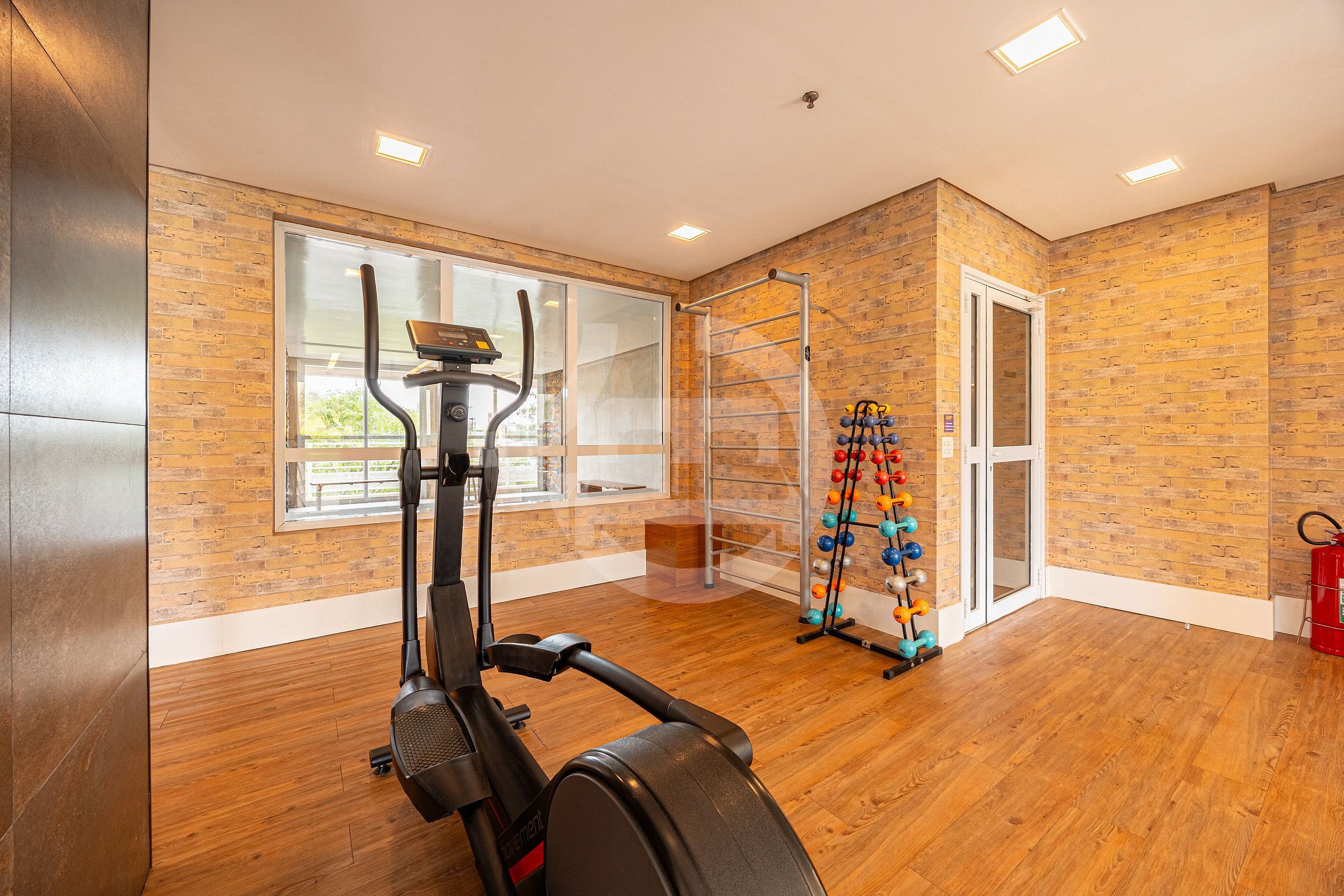 Un gimnasio con una bicicleta estática, una barra de dominadas y un estante con mancuernas.