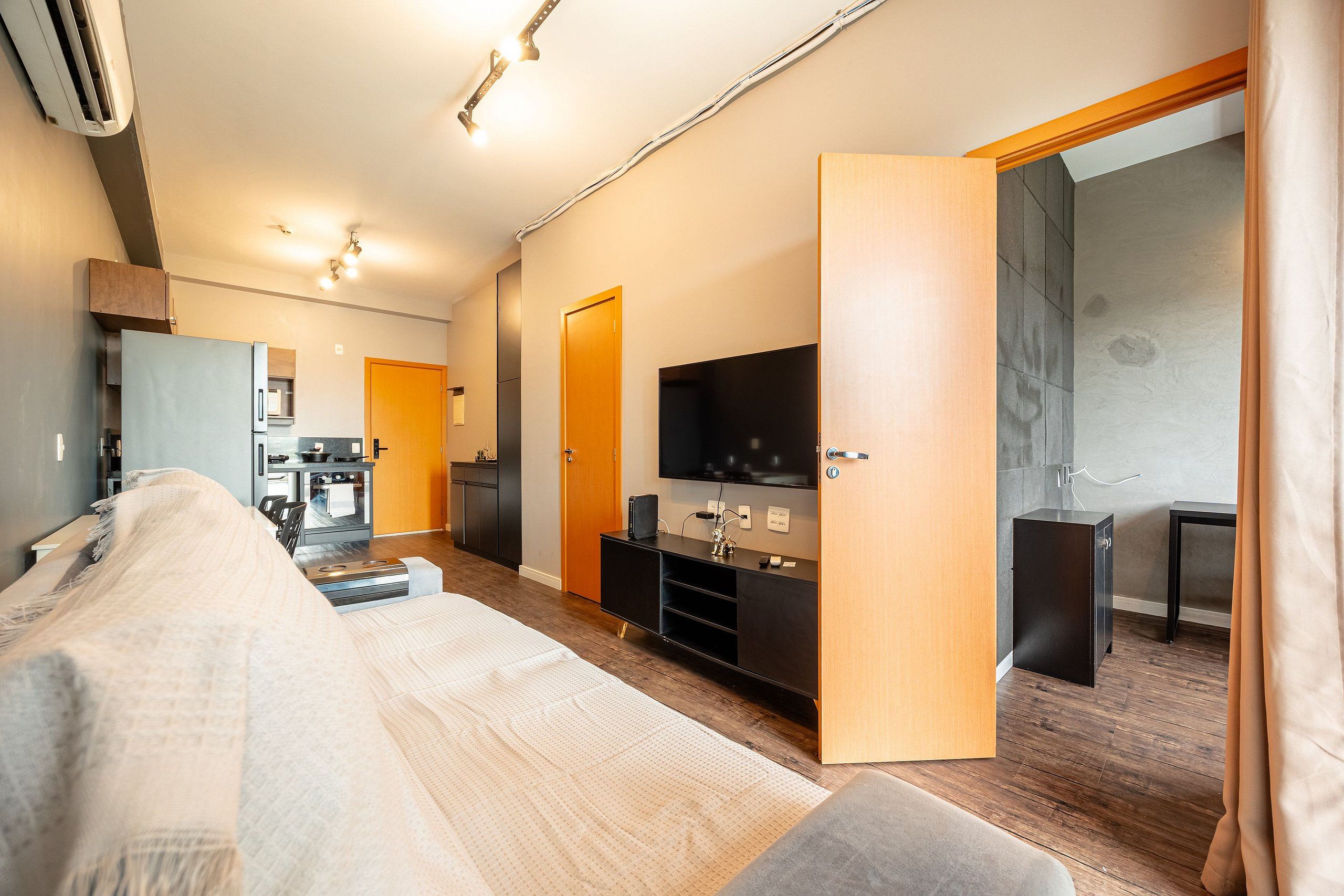 En moderne stue med sofa, TV, køkken og spisebord.