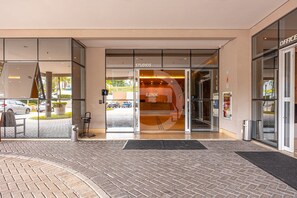 A hotel entrance with glass doors, a sign reading 'STUDIOS,' and a brick-paved area in front.