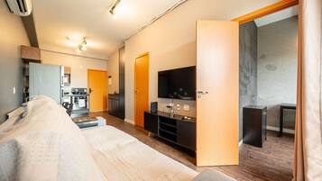 Uma sala de estar moderna com sofá, televisão, área de cozinha e mesa de jantar.