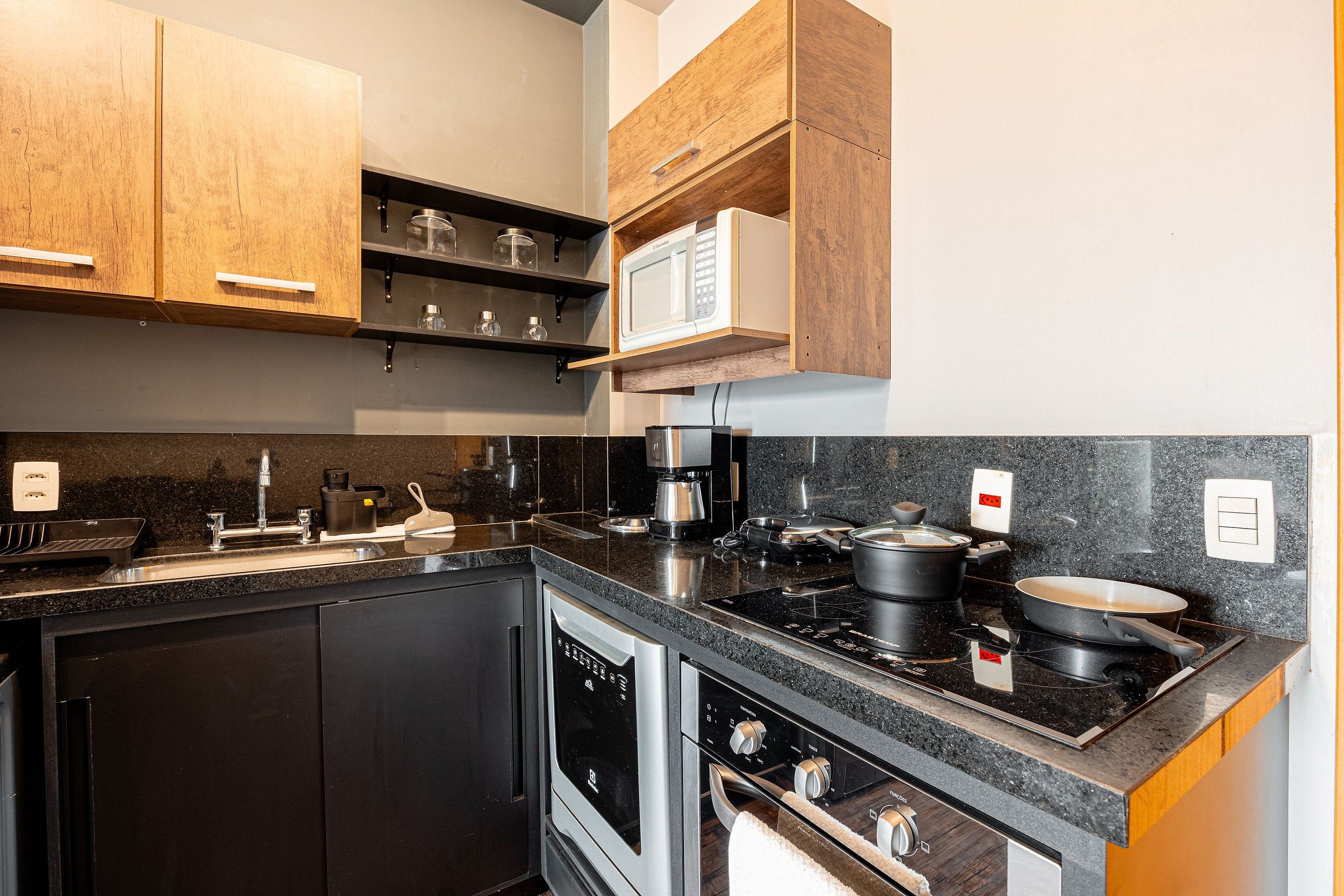 A modern kitchen with a dishwasher, stove, microwave, and wooden cabinets.