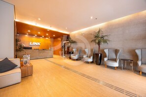 A modern reception area with a reception desk, seating, and a large potted plant. - Premium Modern Studio in Alphaville (Santana de Parnaíba)