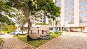 Un edificio moderno con un llamativo letrero 'LINK', senderos pavimentados y coches aparcados.