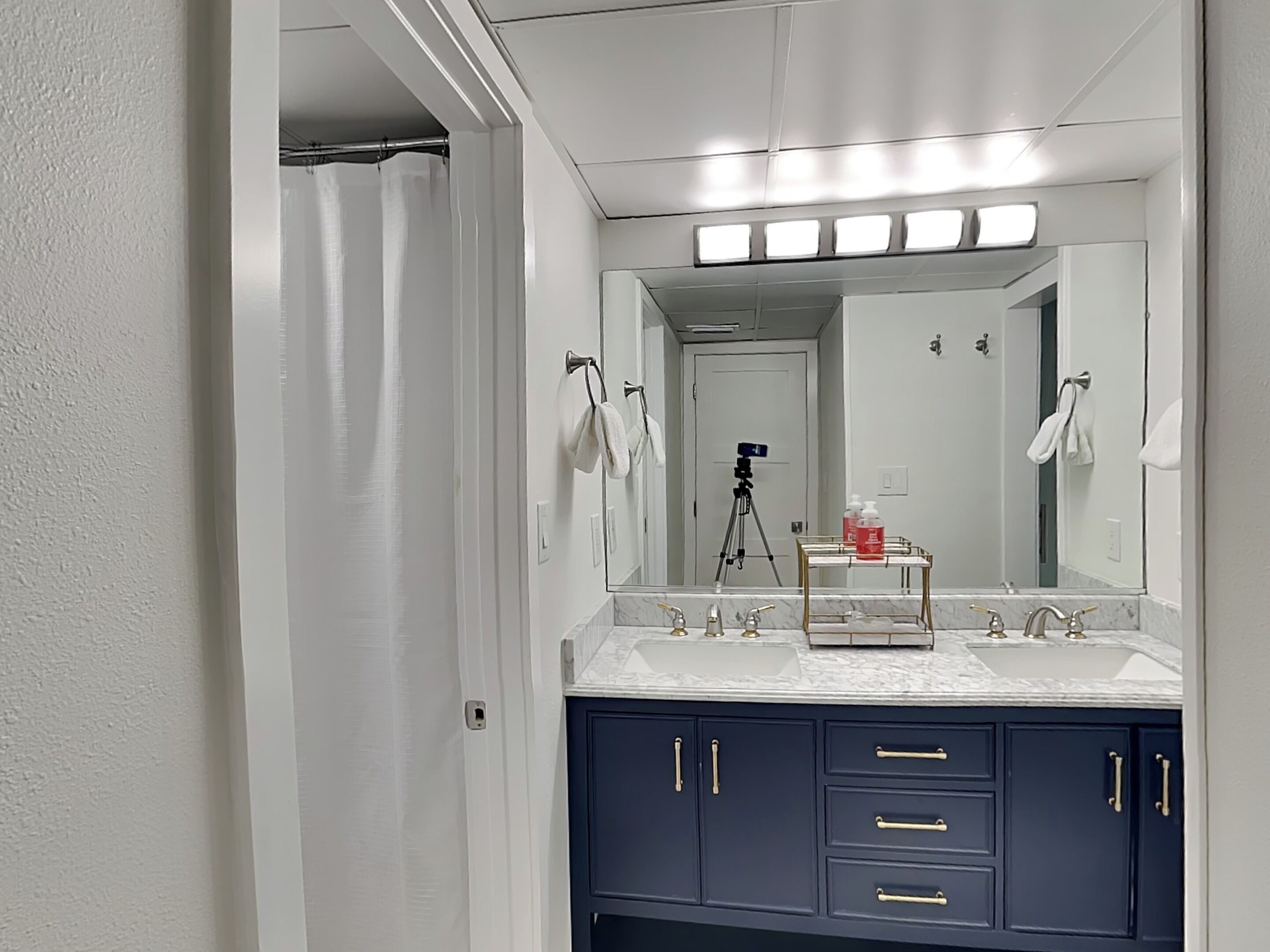Une salle de bain moderne avec un grand miroir, deux lavabos et un meuble-lavabo doté de tiroirs.