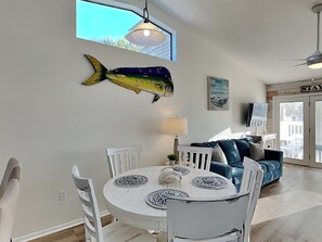 Ein Essbereich mit einem runden weißen Tisch, weißen Stühlen und einer Fischdekoration an der Wand.