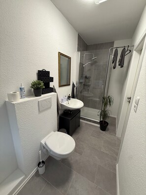 Een douche, handdoeken, zeep, toiletpapier