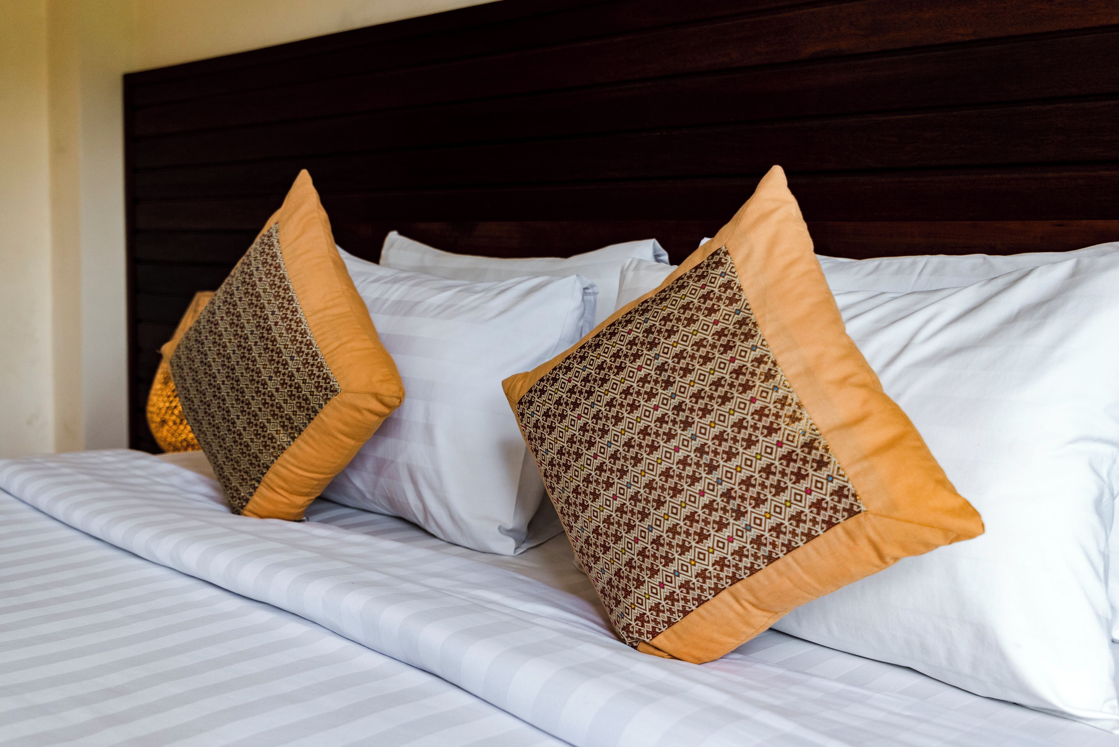A neatly made bed with patterned pillows and a striped comforter.