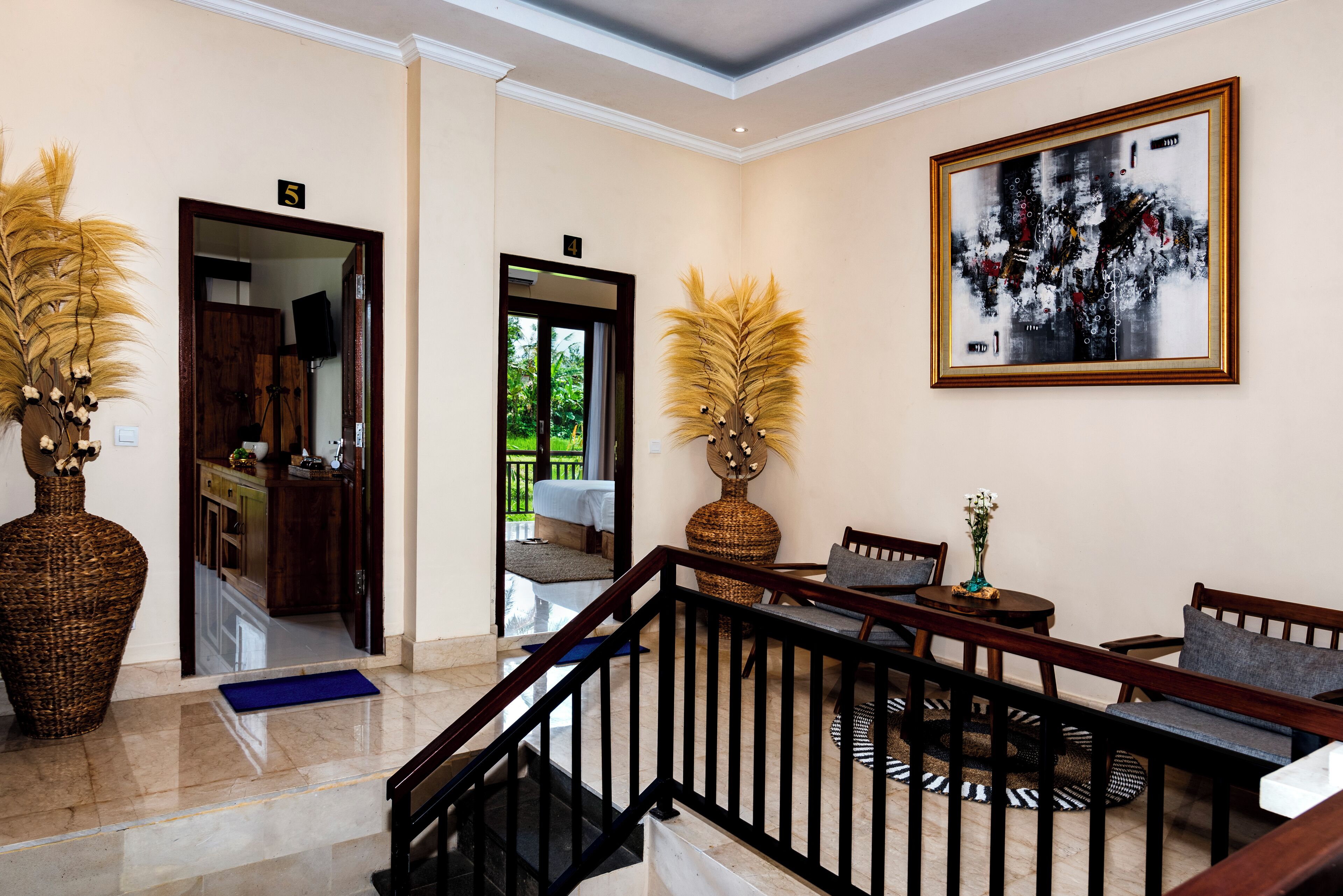 Vestíbulo con escalera, mostrador de recepción y una zona de estar con un cuadro abstracto grande.