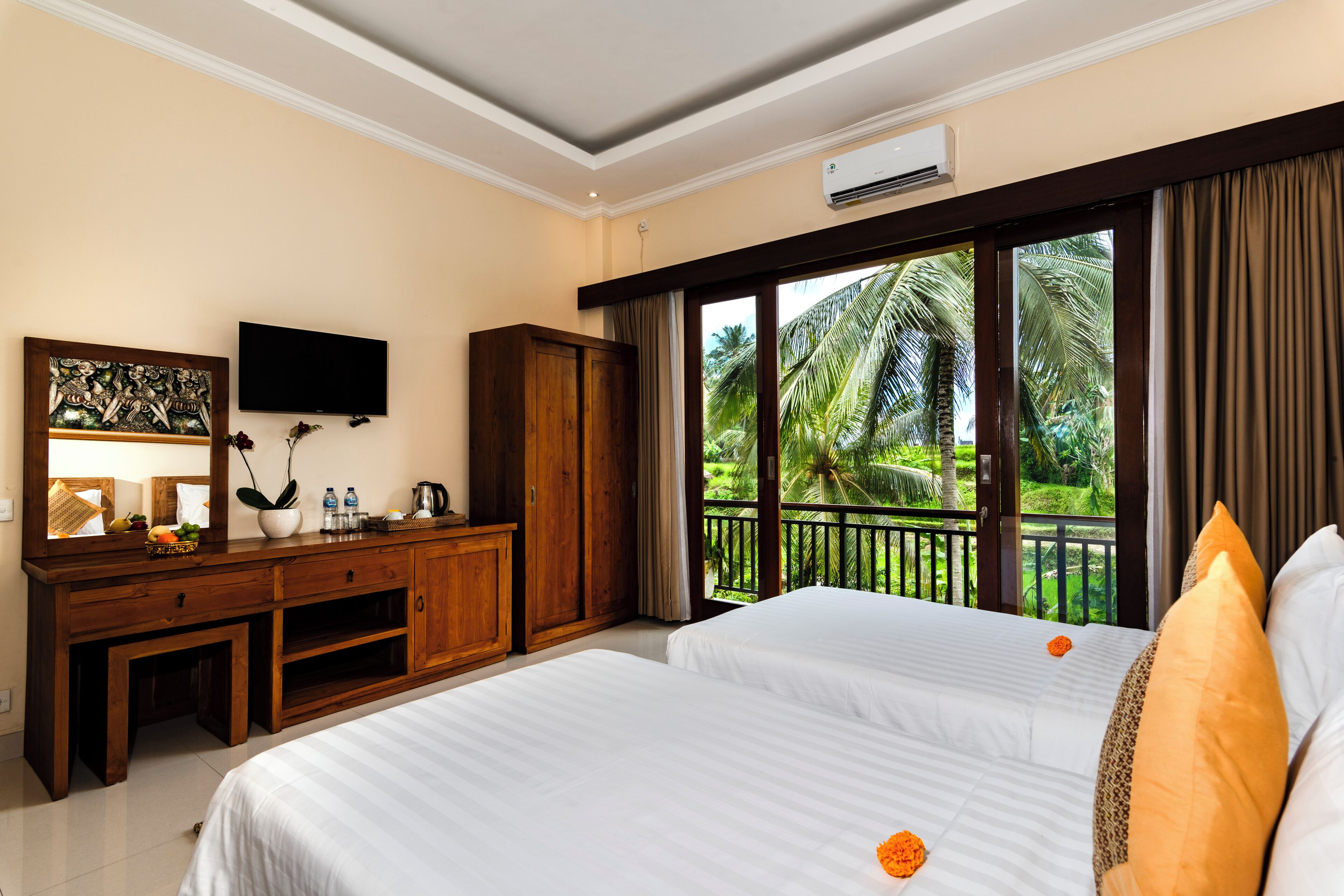 Habitación de hotel con una cama grande, un escritorio de madera, televisión y balcón con vistas a palmeras.