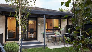 Een modern huis met een overdekte patio, een eethoek en een zichtbare slaapkamer.