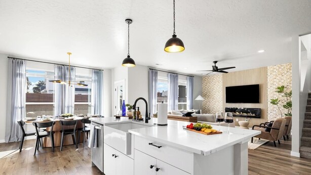 Eine moderne Küche mit Kochinsel, Essbereich mit Stühlen und ein Wohnzimmer mit Sofa und Fernseher.