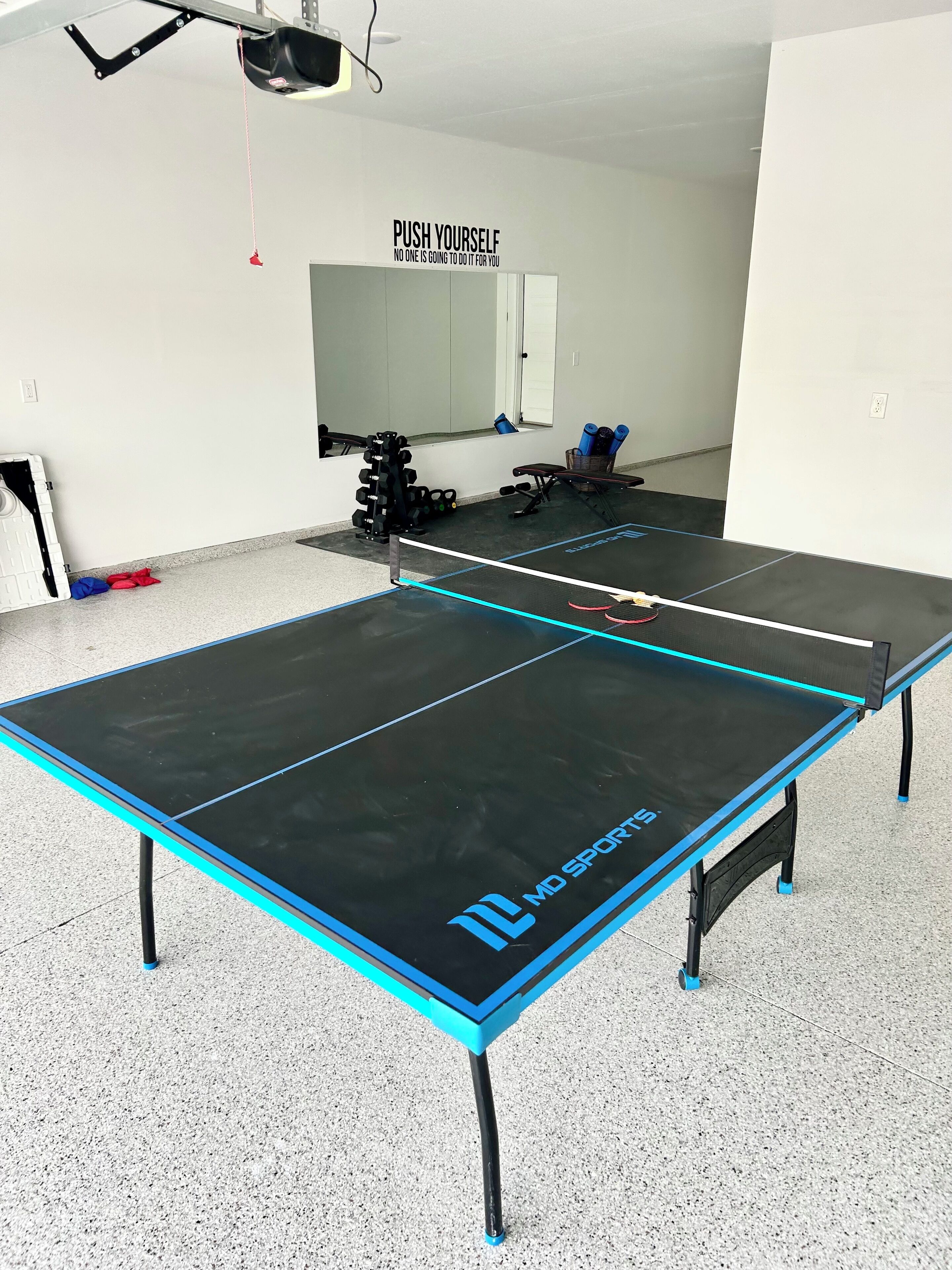 Un tavolo da ping pong con una citazione motivazionale sulla parete.