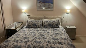 Un dormitorio con una cama, dos lámparas de noche, una mesita de noche y un cuadro en la pared.