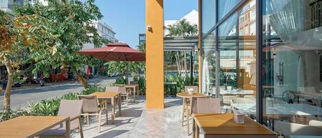 A cafe with outdoor seating, a glass wall, and a view of the street.