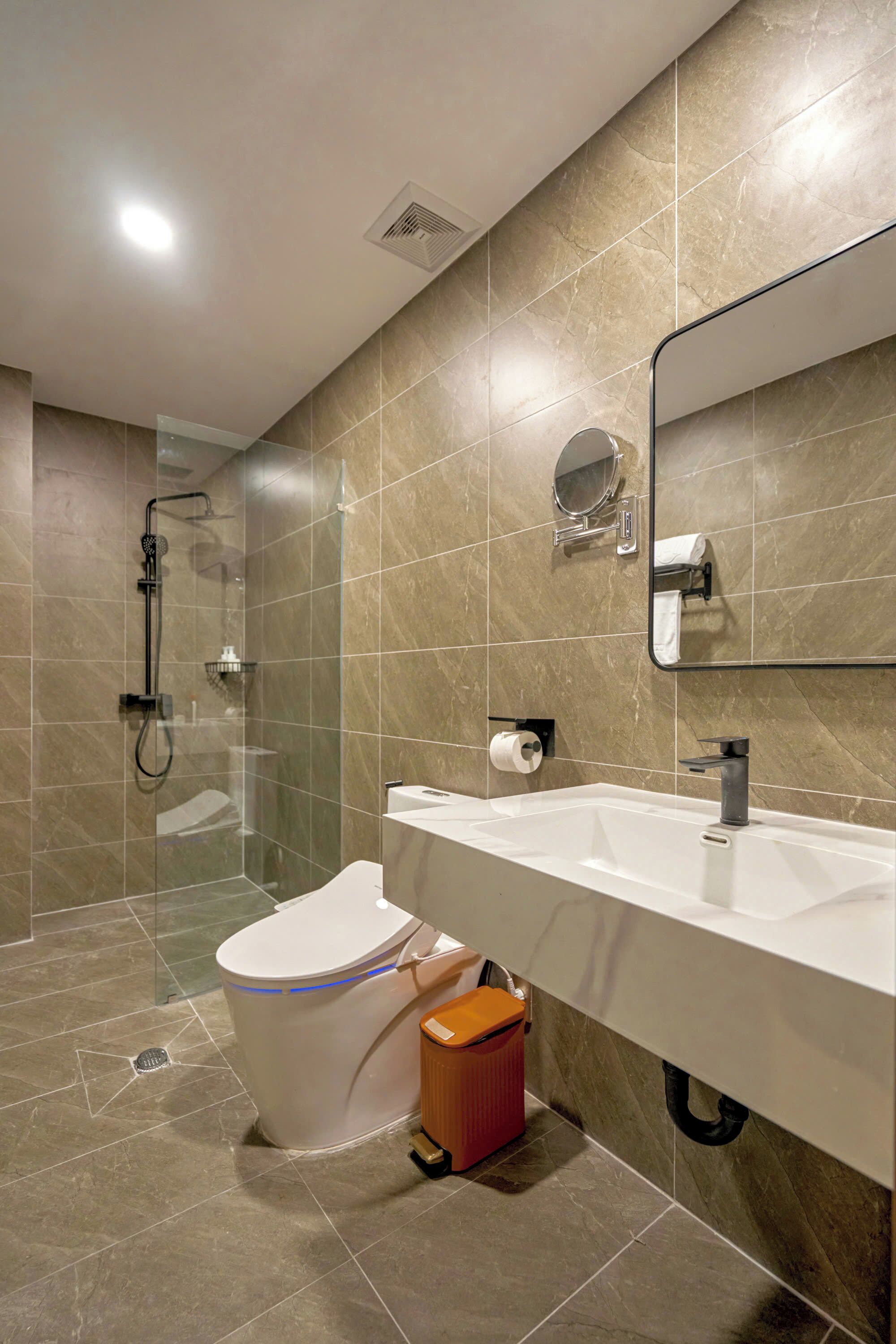 Un baño moderno con ducha, inodoro, lavabo y espejo.