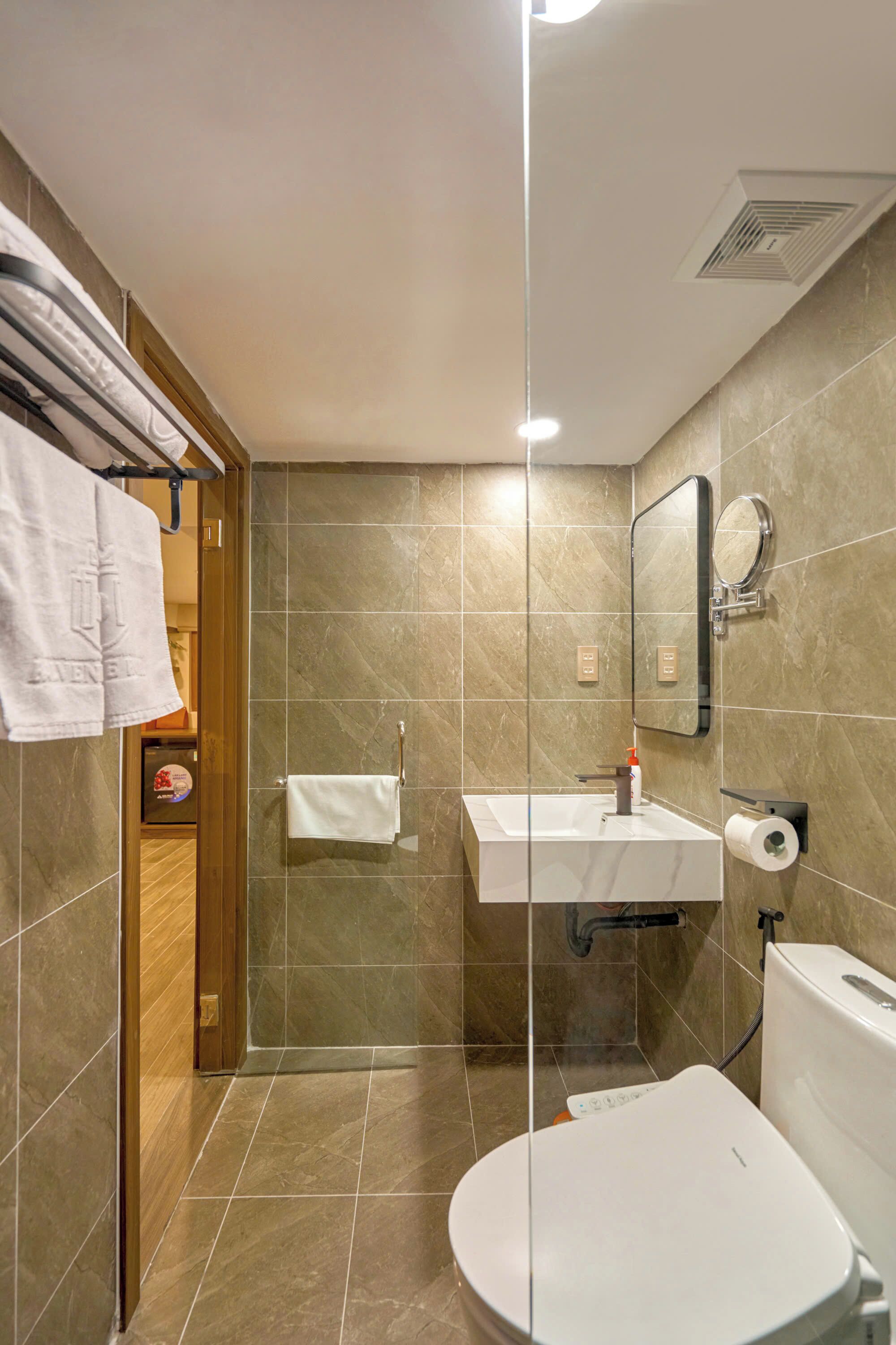 A modern bathroom with a shower, sink, toilet, and a towel rack.