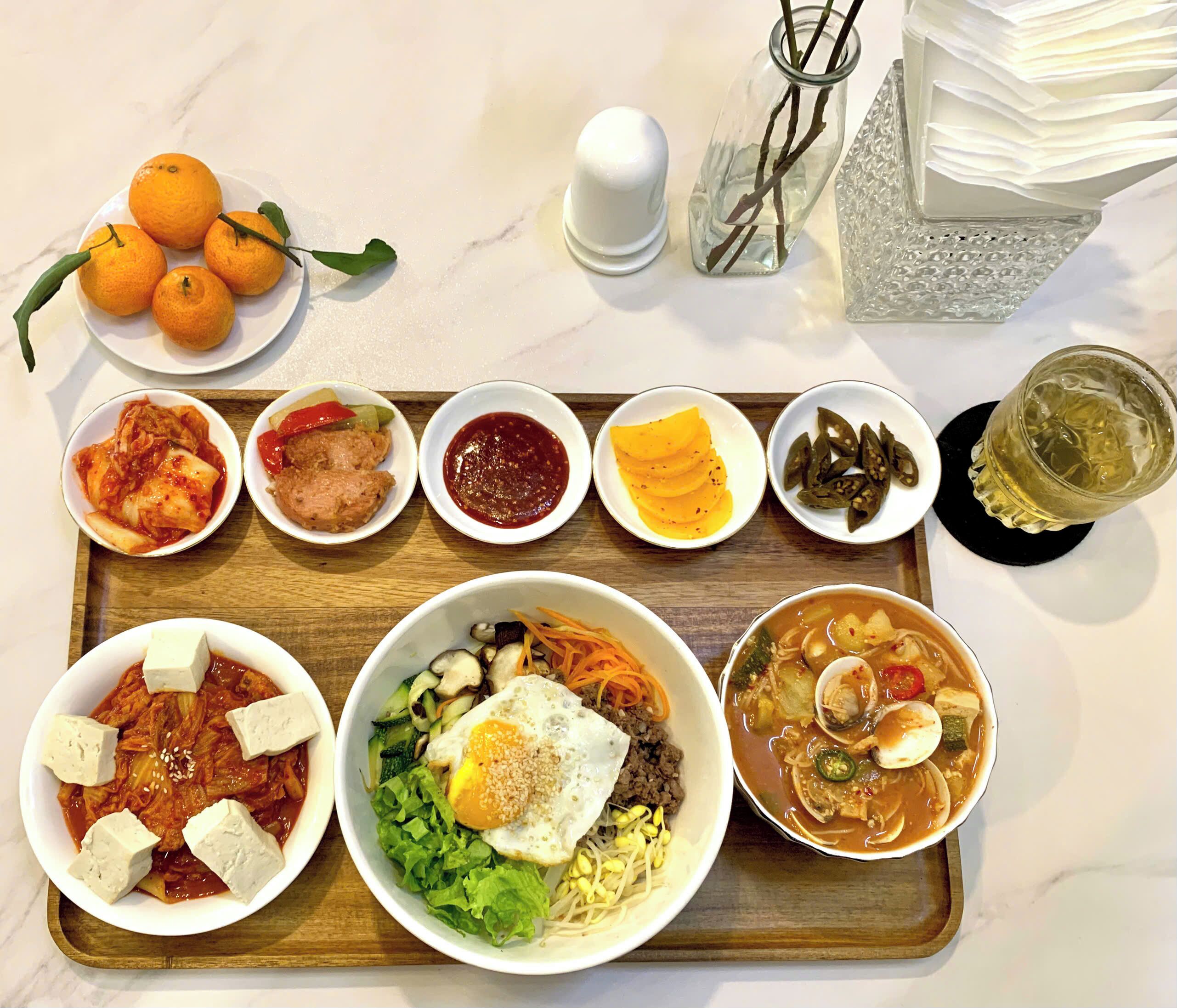 A tray with various dishes including kimchi, tofu, and a bowl of soup.