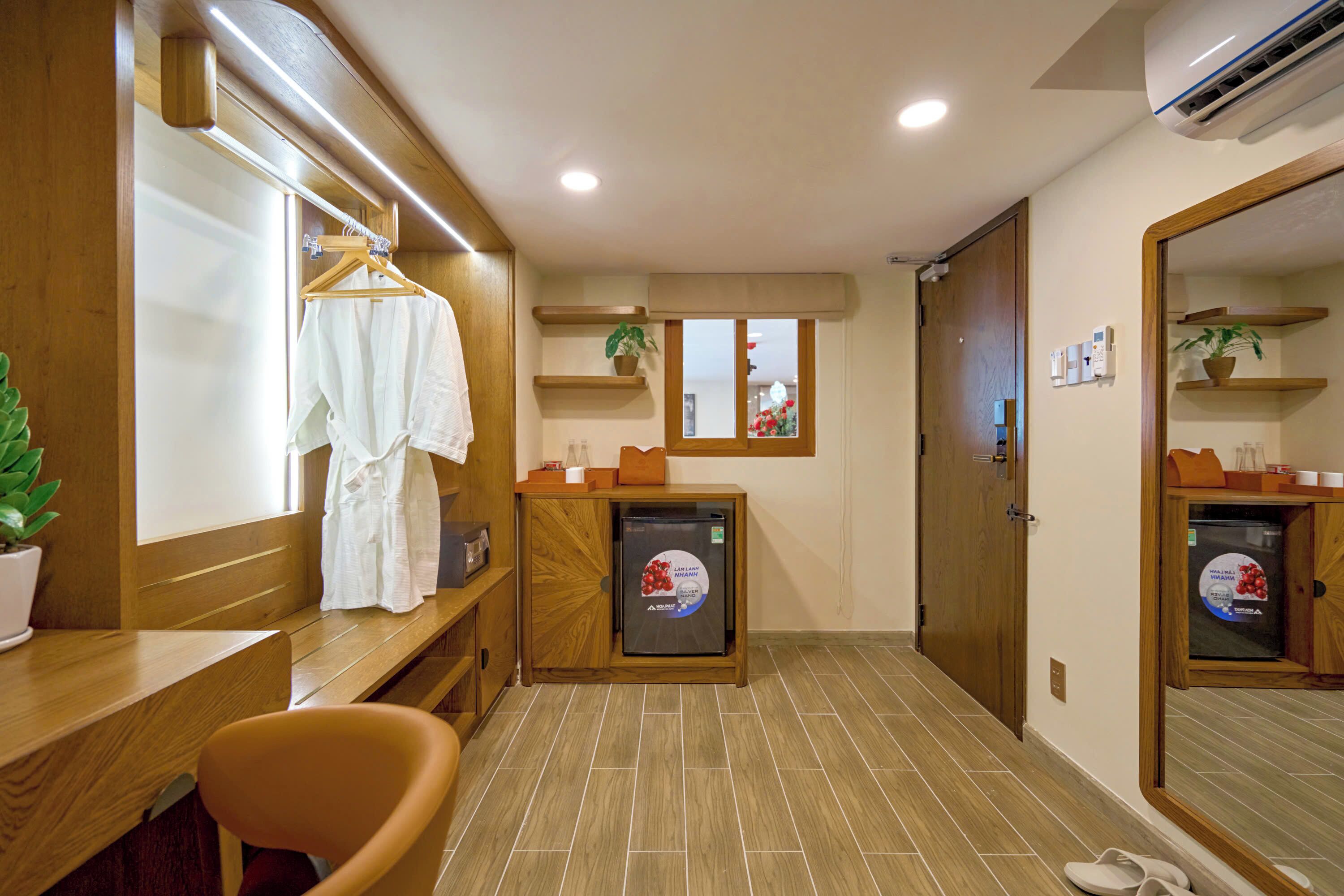 A bathroom with a wooden vanity, a towel rack, a small refrigerator, and a mirror.