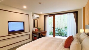 A hotel room with a bed, a desk with a computer, a TV, and a window with a view of greenery. - BALVENIE HOTEL Phu My Hung SECC (Ho Chi Minh City)