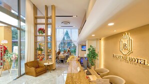 A hotel reception area with a marble counter, seating, and a large window. - BALVENIE HOTEL Phu My Hung SECC (Ho Chi Minh City)