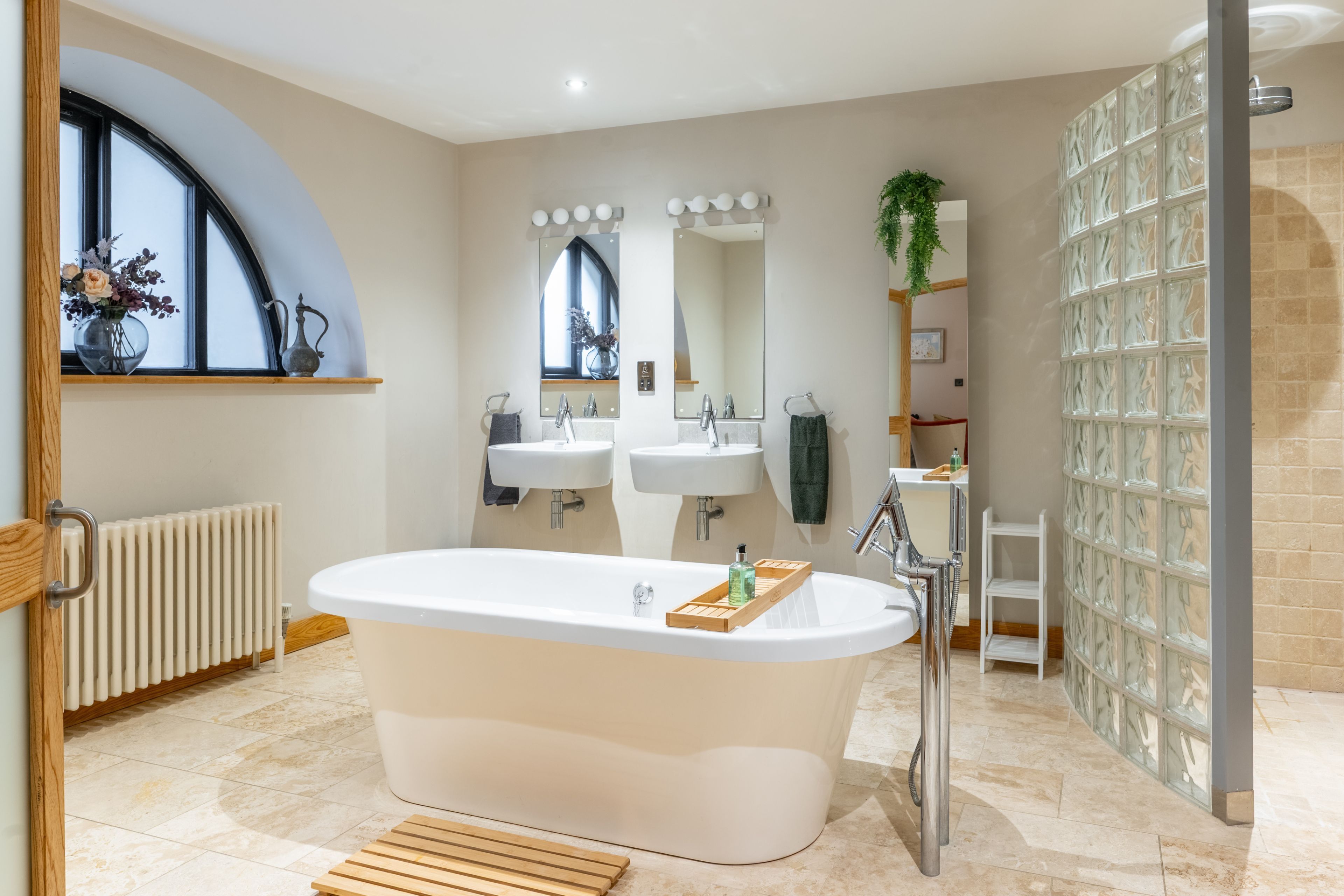 Un baño moderno con una bañera independiente, dos lavamanos, un espejo grande y una zona de ducha.
