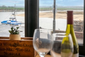 A view from a window overlooking a river with a boat docked on the left. - 16 the Granary, Wells-next-the-Sea, Norfolk (Wells-next-the-Sea)