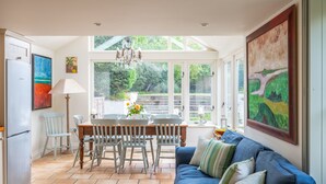 A bright kitchen with a dining table, chairs, and a blue sofa. - Littlefold, Brancaster, Norfolk (Brancaster)