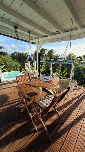 A wooden deck with a hot tub, a table, and two hammocks. - Bwaflo – Lodge with a hot tub in Martinique, an outdoor kitchen, and a beach within walking distance   (Sainte-Luce)