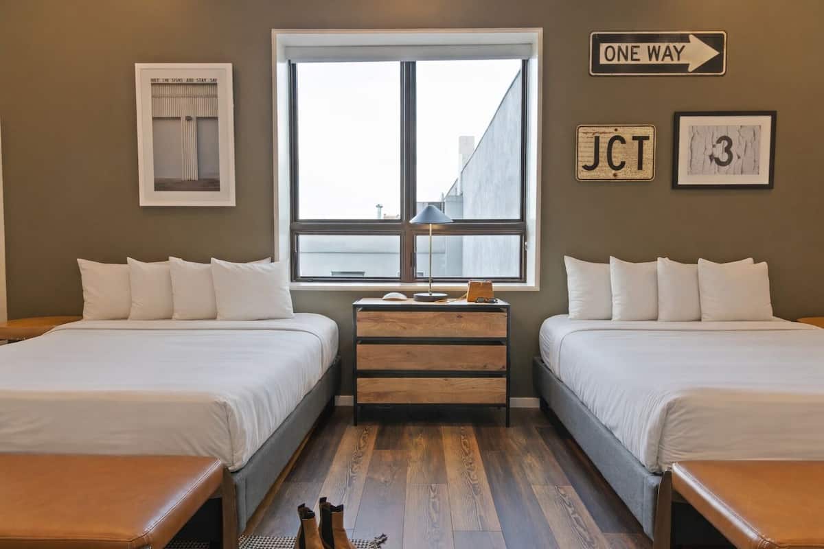 A room with two beds, a window, a dresser, and a sign indicating 'ONE WAY'.