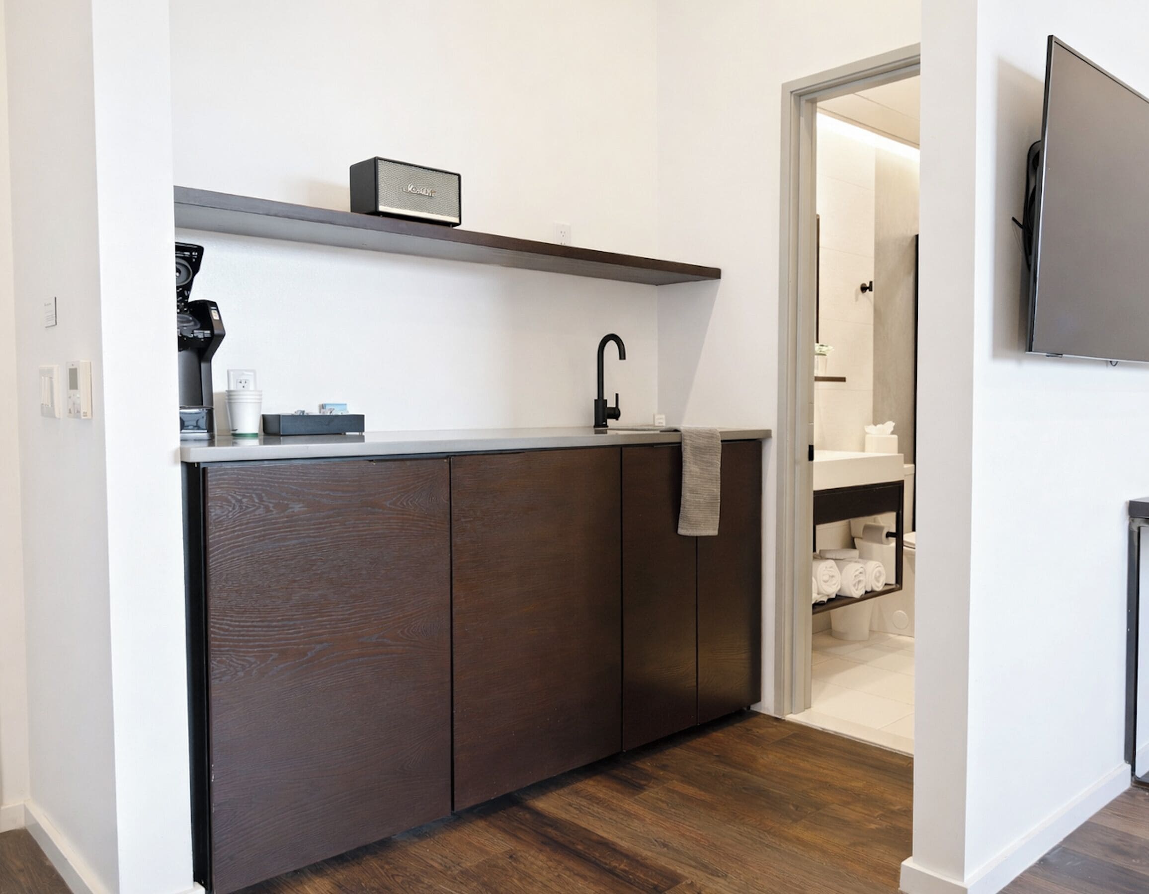 A modern kitchen with dark wood cabinets, a countertop, a coffee machine, and a small speaker.