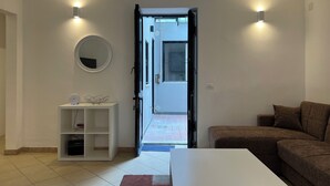 Una sala de estar moderna con un sofá blanco, una mesa de centro blanca, un espejo redondo y una estantería blanca.