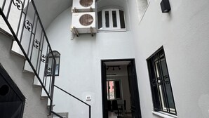 Una escalera estrecha conduce a una habitación con ventana y puerta. Dos unidades de aire acondicionado están instaladas en la pared, encima de la escalera.