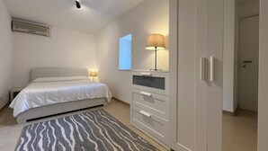 Un dormitorio con cama, mesita de noche, lámpara, armario y espejo.