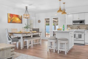 Una cucina moderna con mobili bianchi, un'area pranzo con tavolo e sedie in legno e un'ampia finestra.
