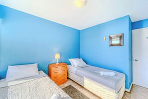 A room with two beds, a wooden dresser, a small mirror, and a door.
