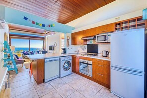 A compact kitchen with a washing machine, oven, microwave, and refrigerator.